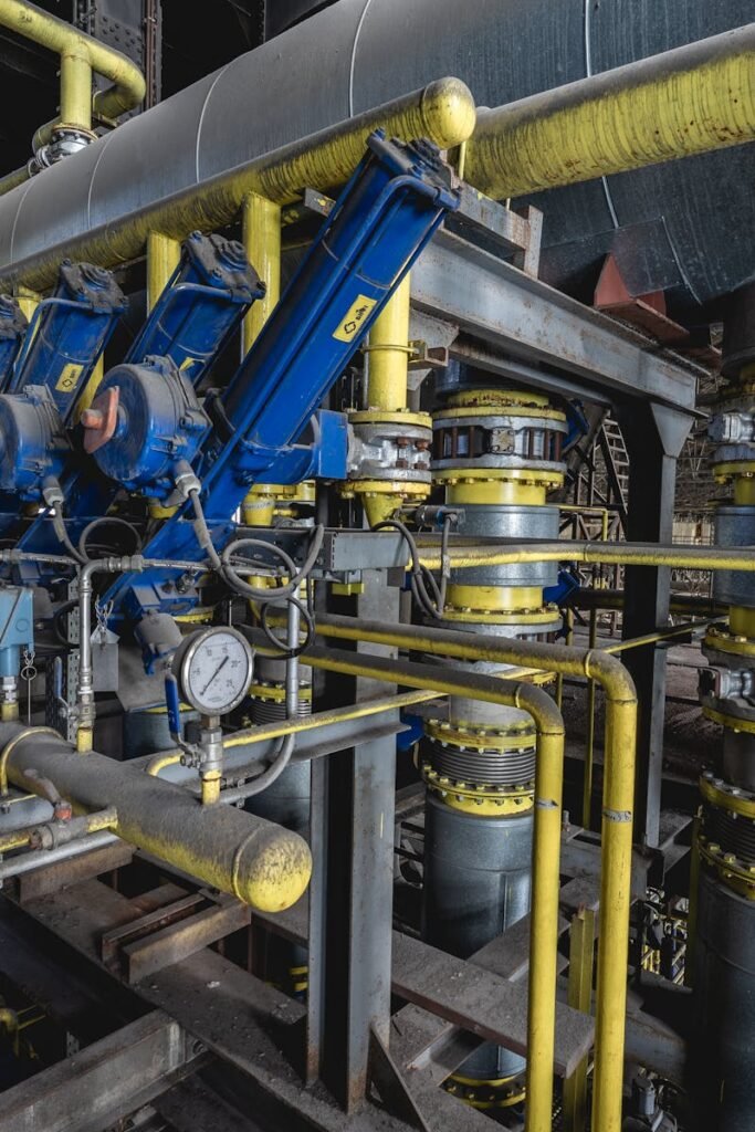 pexels-photo-17728782-17728782-1 A detailed view of an industrial machine room featuring complex blue and yellow equipment and piping.